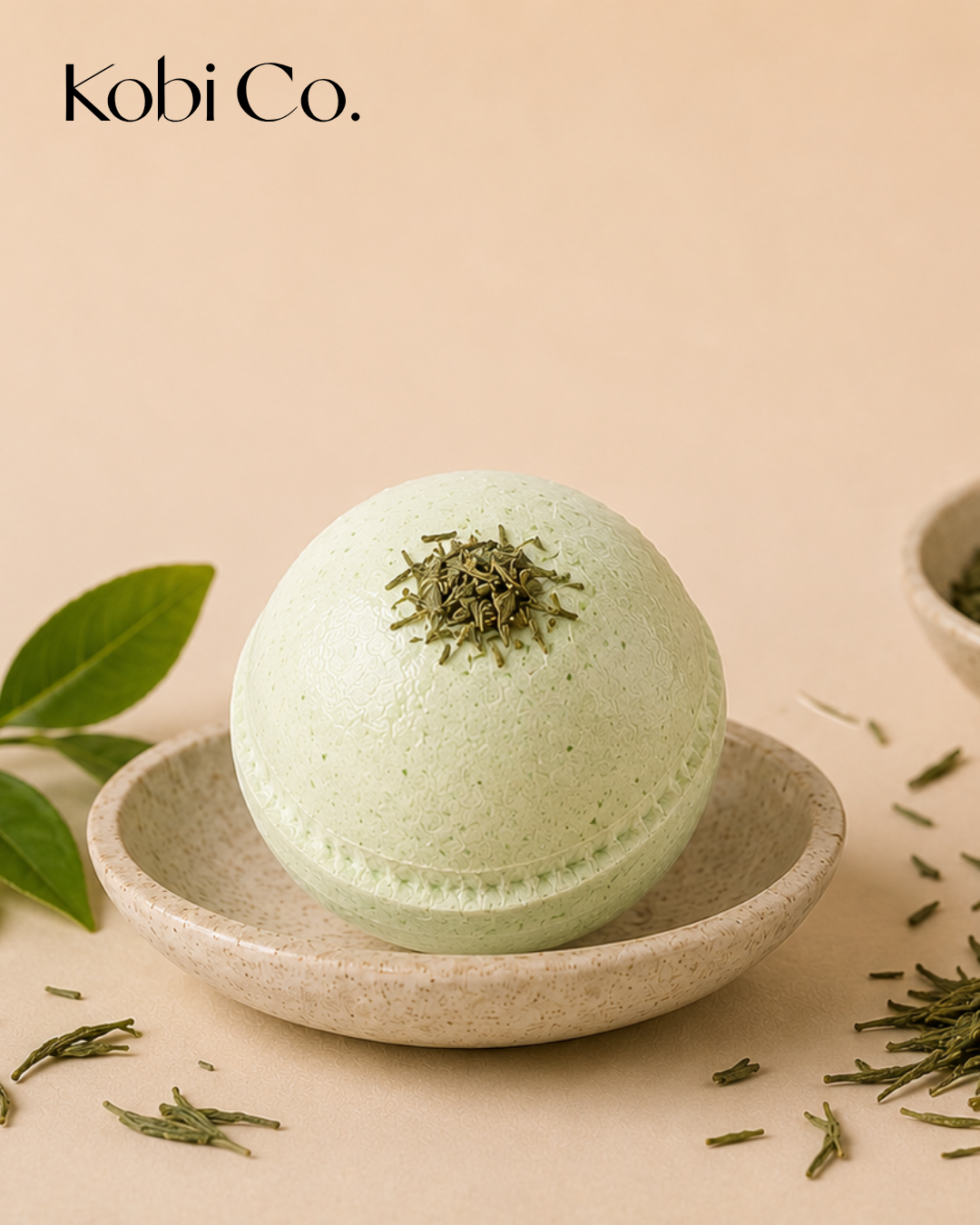 Kobi Co. Green Tea Bath Bomb displayed with green tea leaves in a luxury spa-inspired setting