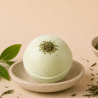 Kobi Co. Green Tea Bath Bomb displayed with green tea leaves in a luxury spa-inspired setting